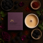 A styled flat-lay of a candle product showing a deep purple rectangular box labeled 'Blackberry & Saffron' next to a white ceramic candle jar filled with pale golden wax. The scene is surrounded by blackberries, rose petals, green leaves, saffron threads, and a dark textured surface.