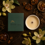 A dark green candle box labeled 'ORCHID & MIDNIGHT AMBER' is arranged on a dark rustic surface beside a white candle vessel with creamy wax and a wick, surrounded by orchid flowers, amber pieces, and botanical props.